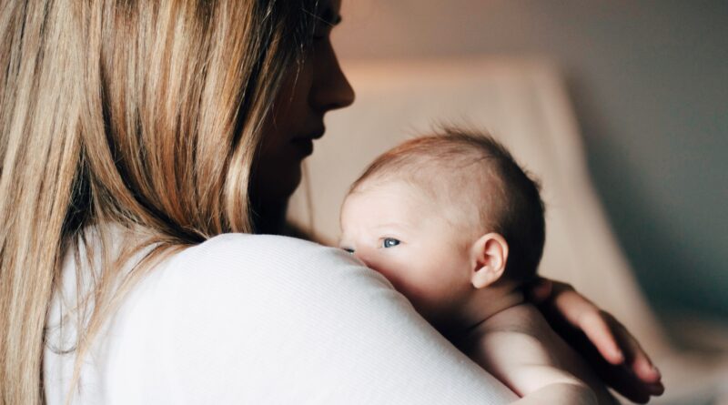 woman in white shirt carrying baby