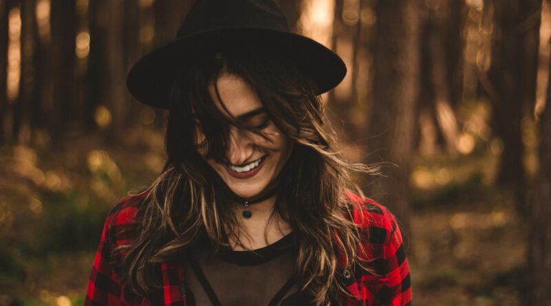 woman in fedora hat surrounded by trees